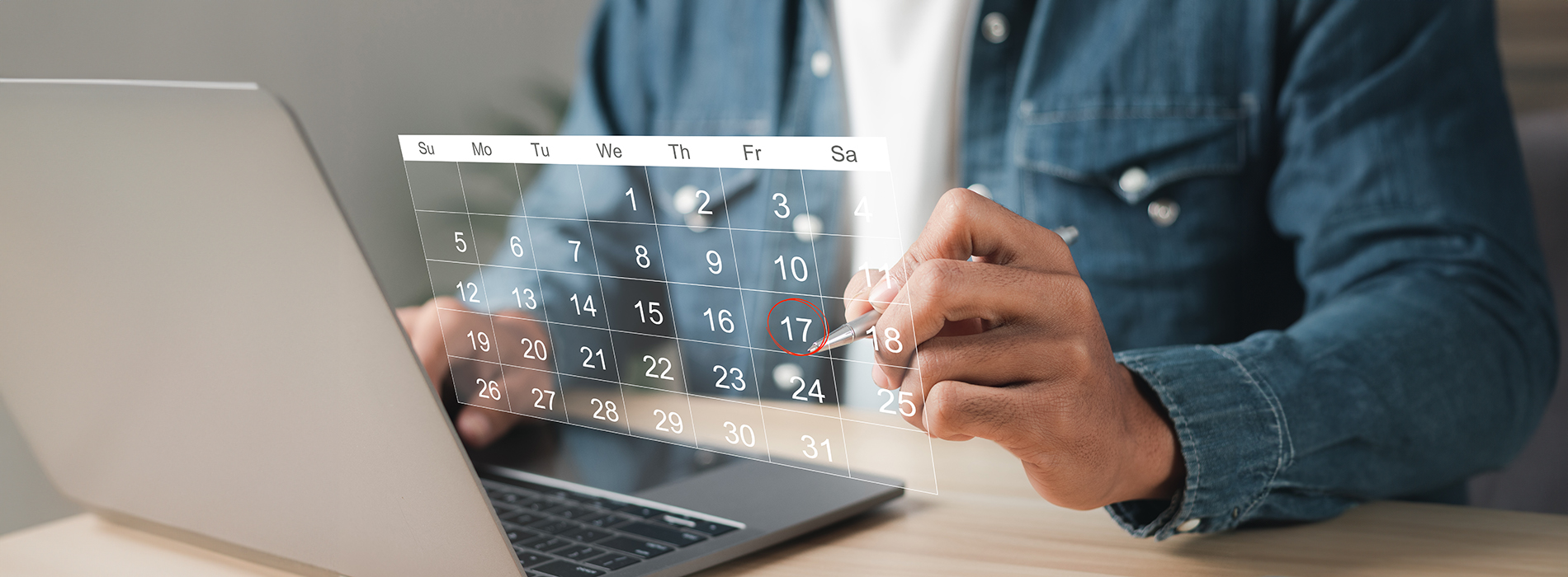 A person working on a laptop with a calendar displayed, showing the month of December.