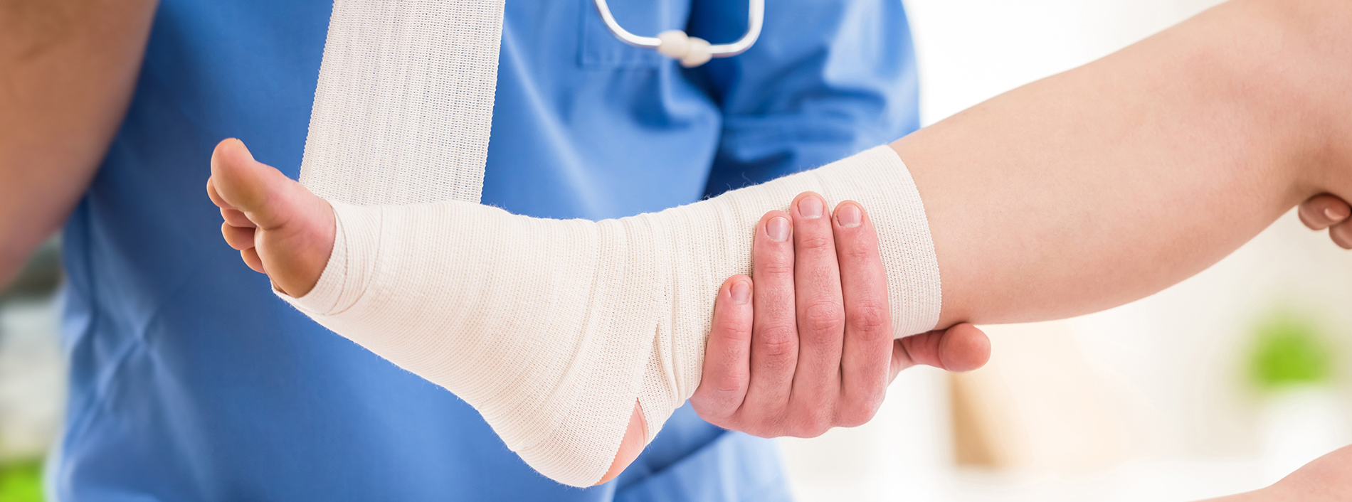 A healthcare professional in a white coat and stethoscope, with an arm casted, is receiving support from another person.