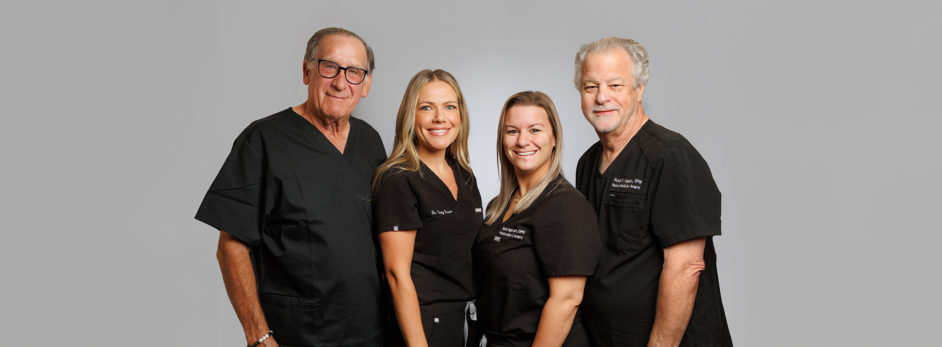 This image shows a group of four individuals, presumably professionals given their attire and the setting, posing together for what appears to be a promotional or professional photograph.