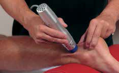 An image featuring a person applying a blue device to someone s leg, possibly for therapy or treatment.
