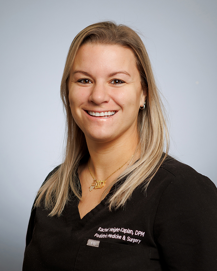 A smiling woman with blonde hair, wearing a black shirt and a name tag, poses for the camera.