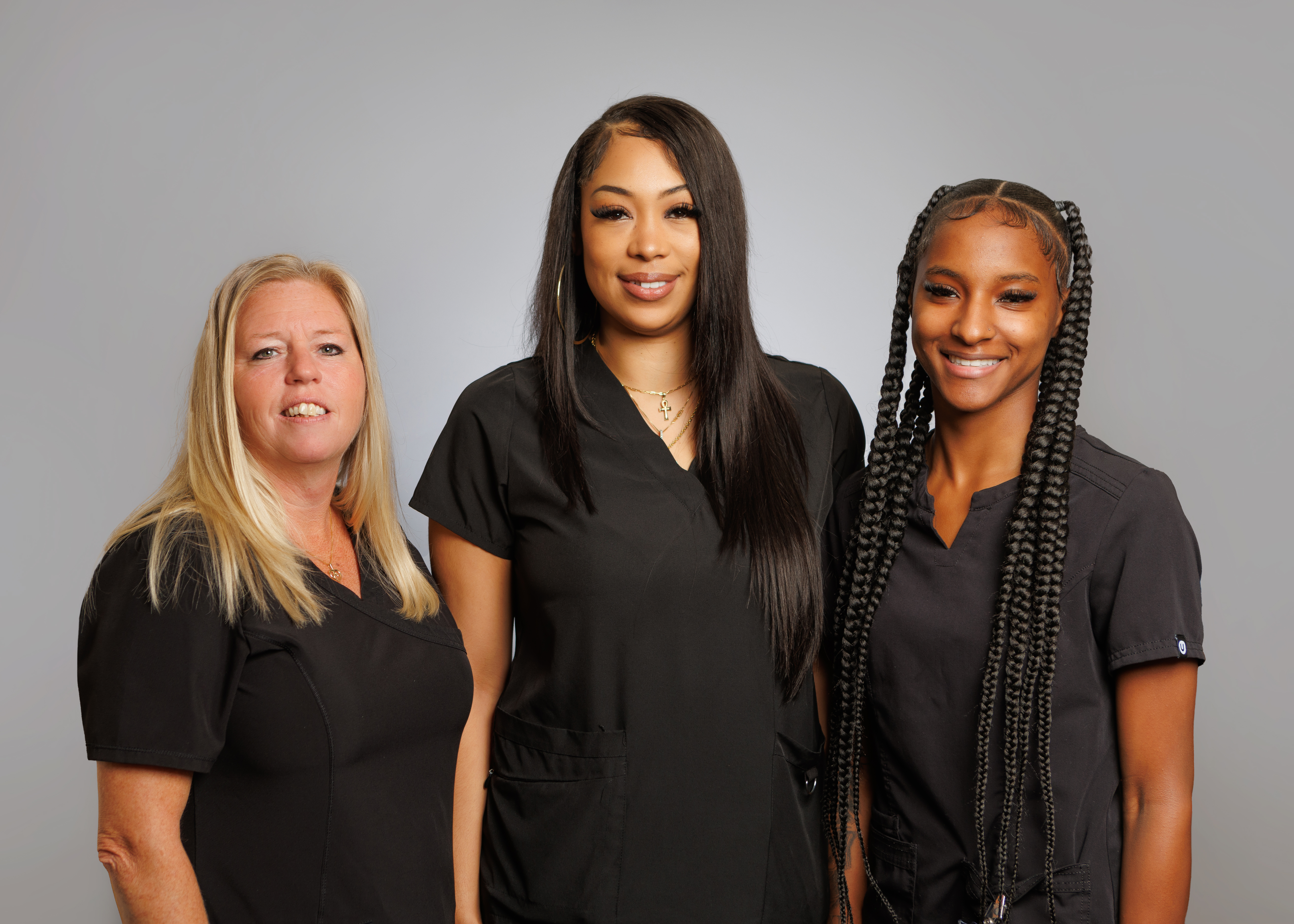 Three individuals in scrubs, likely healthcare professionals, posing together for a group photo.